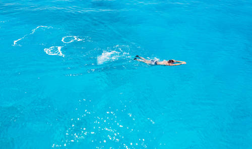Young man swimming in clear sea water.