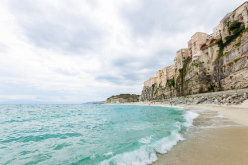 Tropea town and beach coastline of Tyrrhenian Sea with turquoise water, colorful buildings on top of cliff. Santa Maria dell Isola, Calabria, Southern Italy
