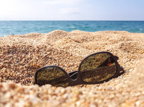 Arena y mar con gafas de sol en primer plano.