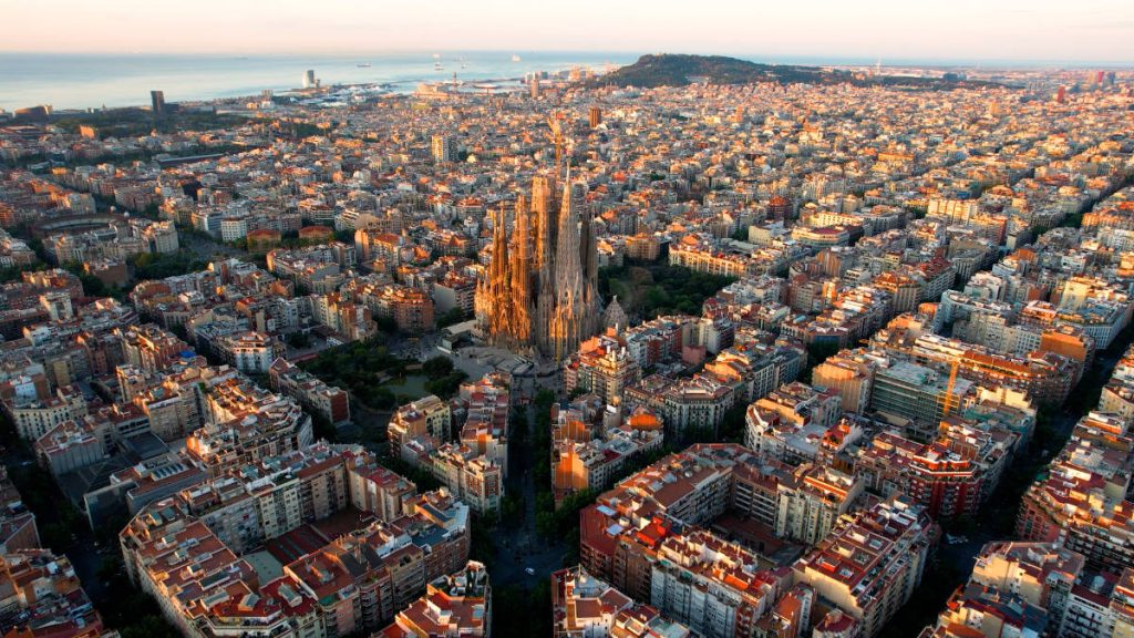 Vista aérea de la ciudad de Barcelona, con la Sagrada Familia en el centro de la imagen y la costa al fondo.