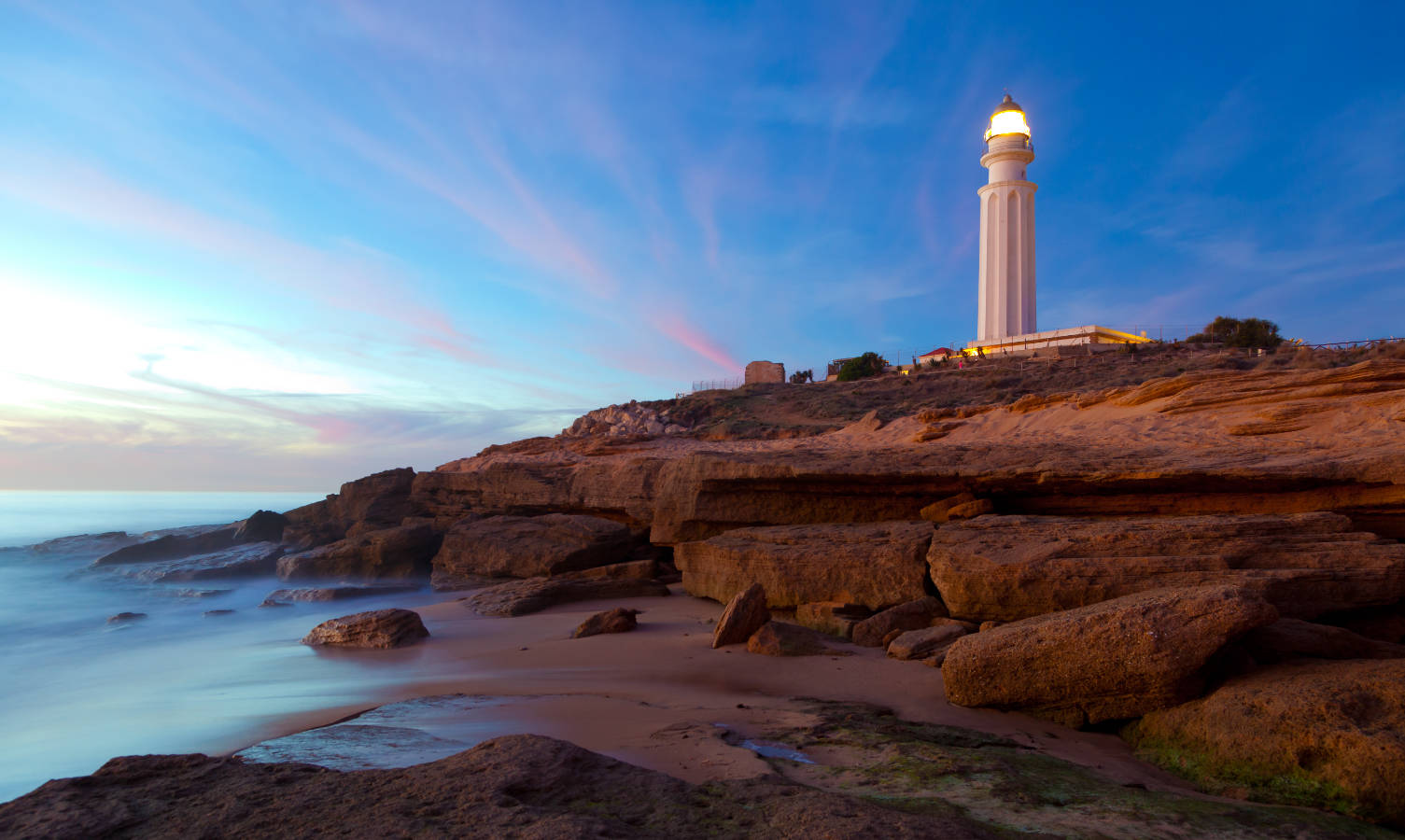 Vista del Faro de Trafalgar, con la arena y el mar en primer plano.